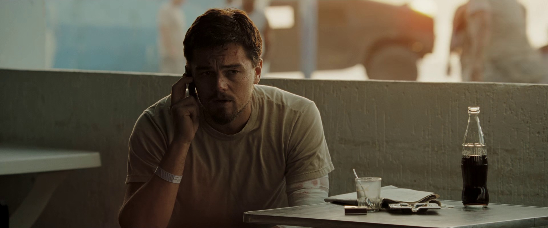 Still from Body of Lies (2008): Leonardo DiCaprio on a phone at a café table