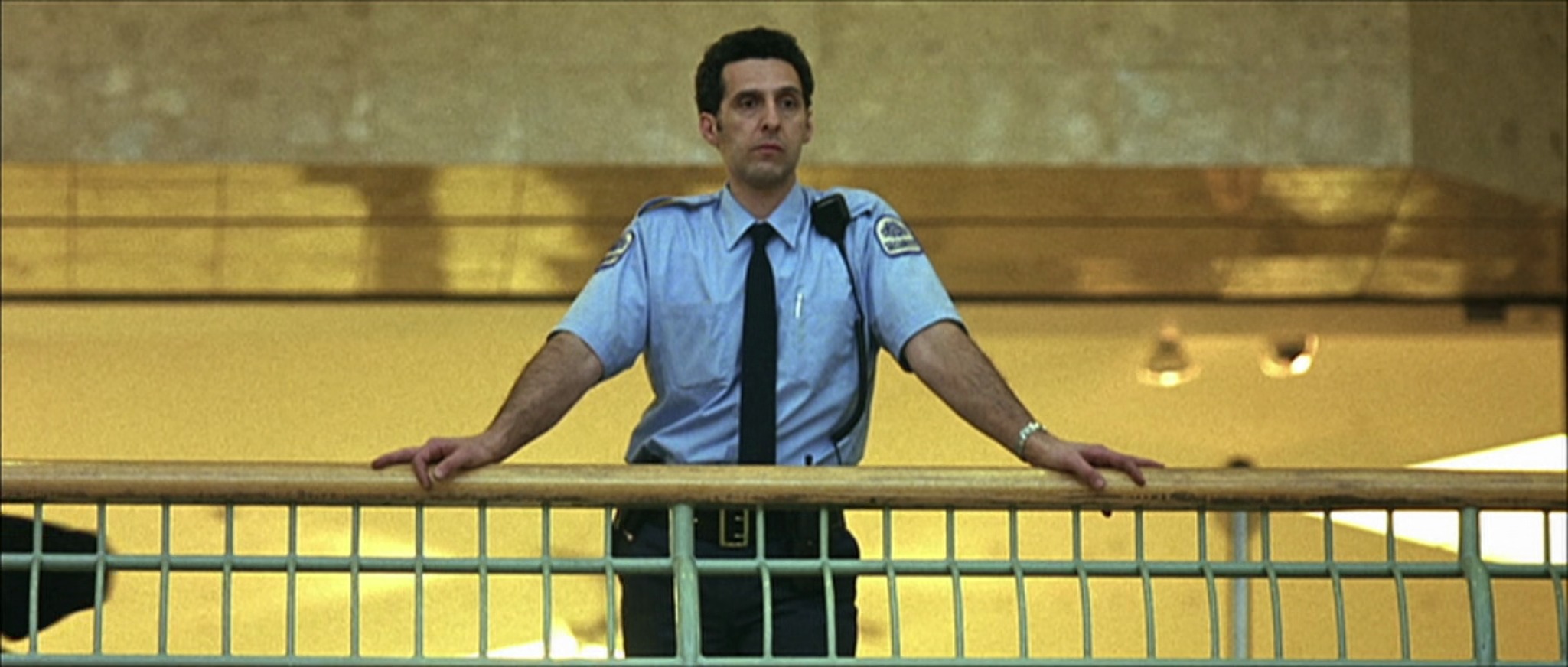 Still from Fear X: John Turturro in a security uniform at a railing
