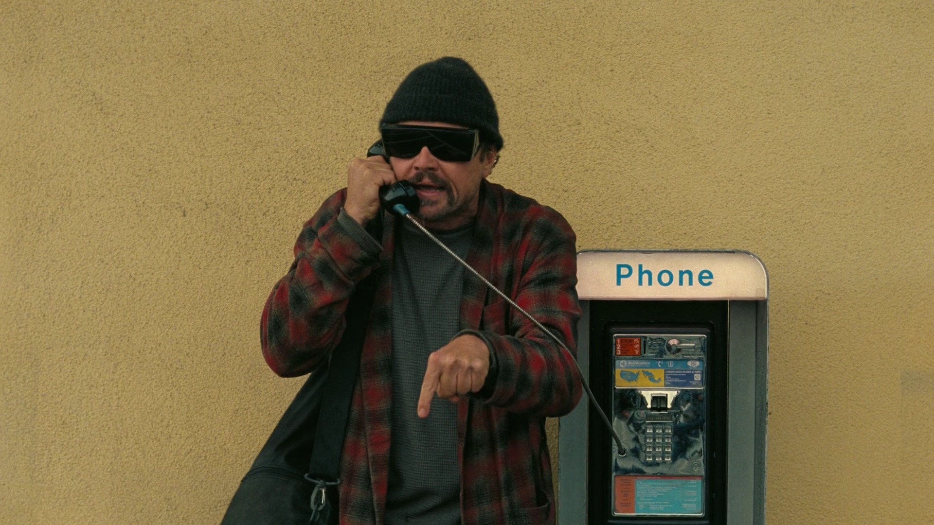 Still from One Battle After Another: a man on a payphone, urgent and pointing